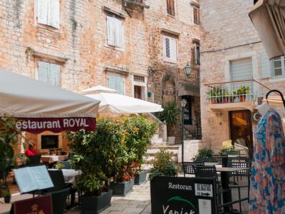 Quaint outdoor dining setup in Trogir, Croatia, featuring rustic stone architecture and restaurant signs.
