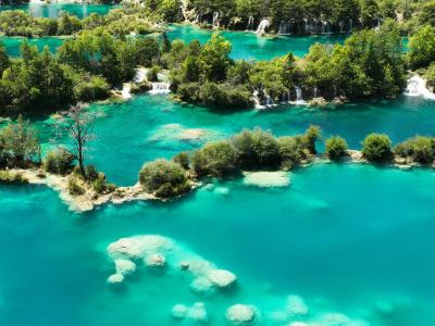 Stunning aerial shot of vibrant turquoise lakes and lush forests at Plitvice Lakes National Park.