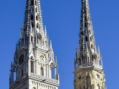 Two iconic Gothic spires of Zagreb Cathedral reaching into a clear blue sky, showcasing Croatian architecture.