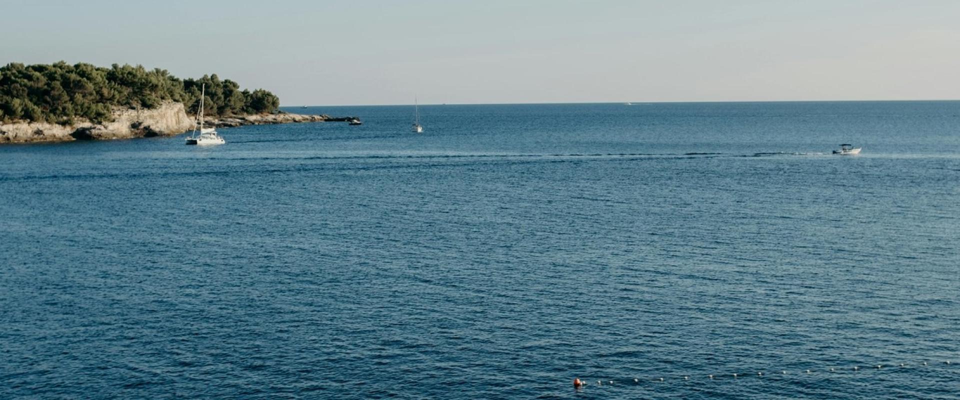 Calm beach scene with sun umbrellas and loungers on a Croatian coastline.
