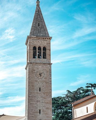 Vertical view of a historic church tower in Novigrad, Croatia against a clear sky.