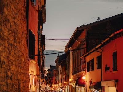 Lively street in a Croatian town at twilight filled with people and historic architecture.