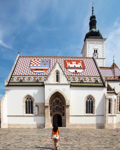 a person standing in front of a white building with a red roof